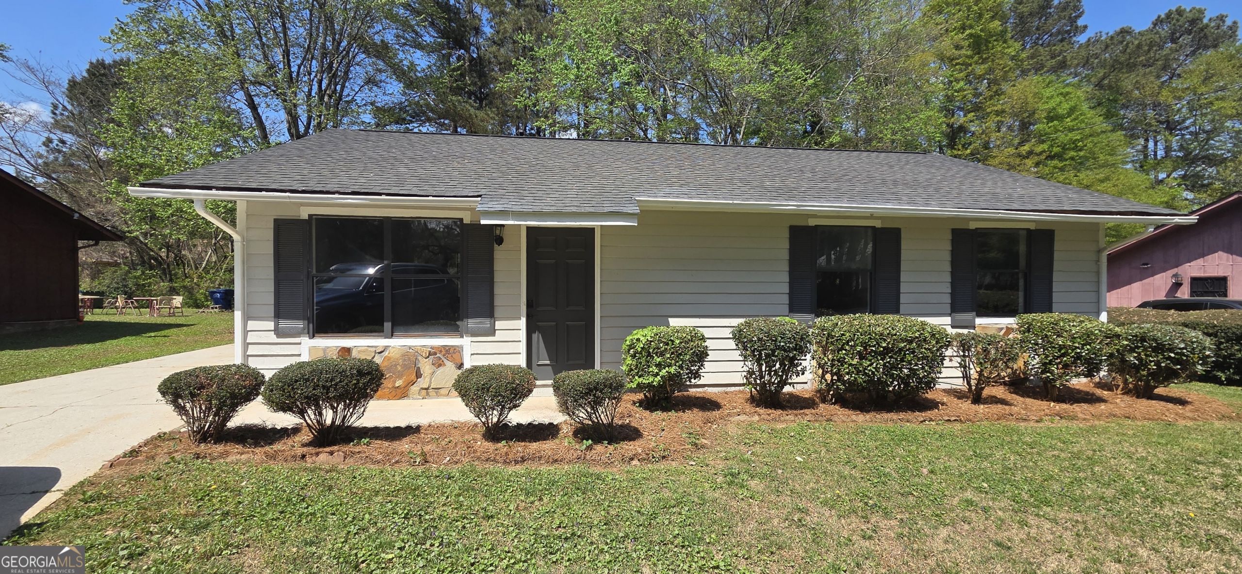 Exterior front view of a single-story ranch-style home at 445 Wilson Mill Rd SW, Atlanta, GA, featuring light siding, dark shutters, and professional landscaping.